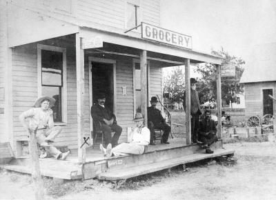 A group of guys idle their time on the front porch of the grocery.